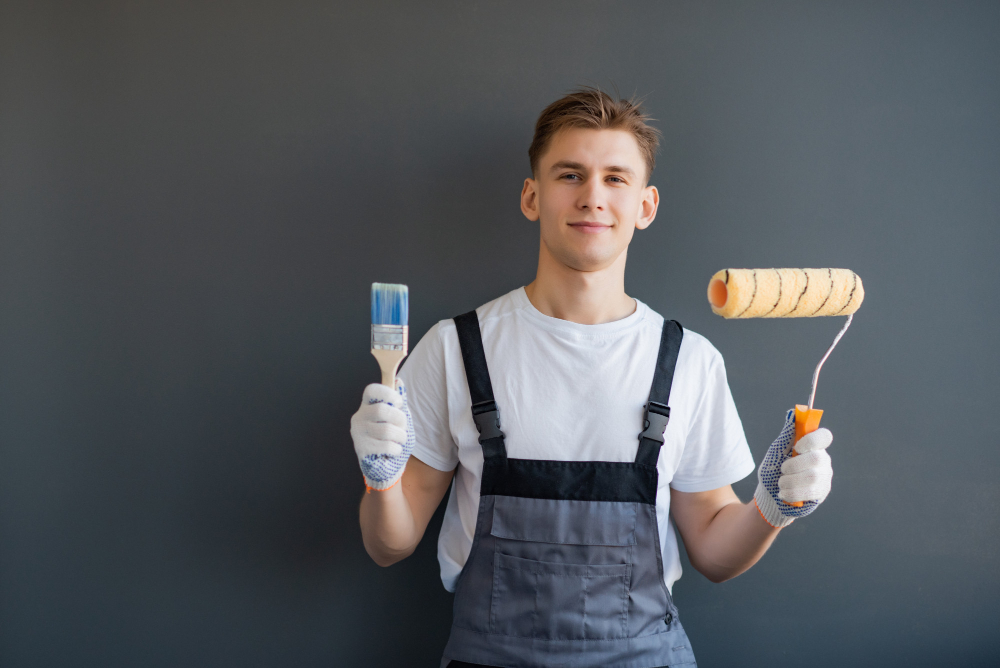 handsome young smiling worker with paint roller brush